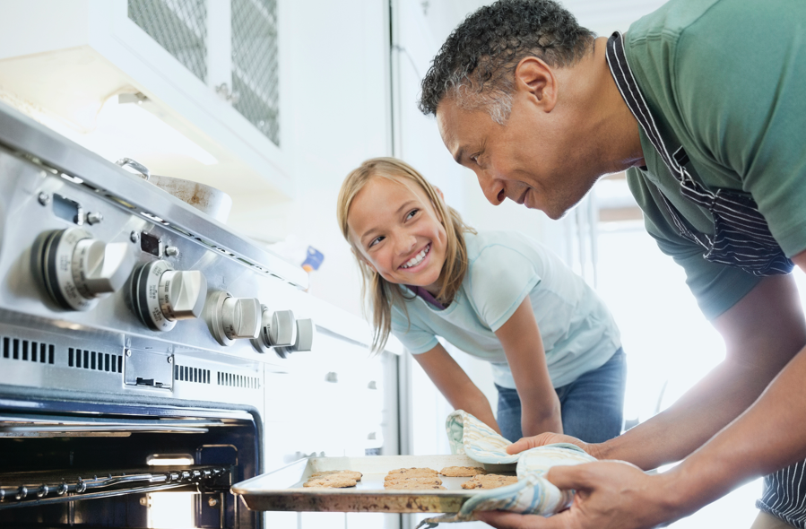 Man and child taking cookies out of oven | BCBS of Tennessee Man and child taking cookies out of oven | BCBS of Tennessee